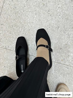 Person trying on black Mary Jane style shoes on a light floor.