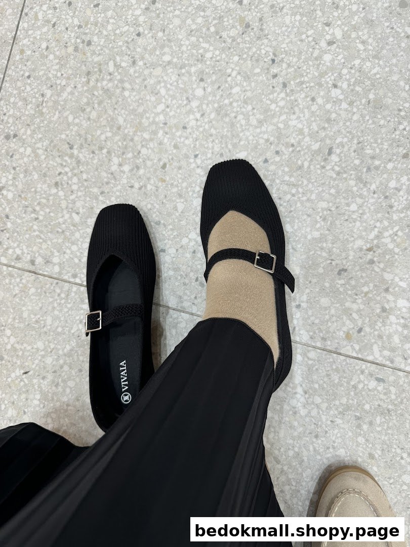 A person wearing black VIVAIA shoes on a tiled floor.