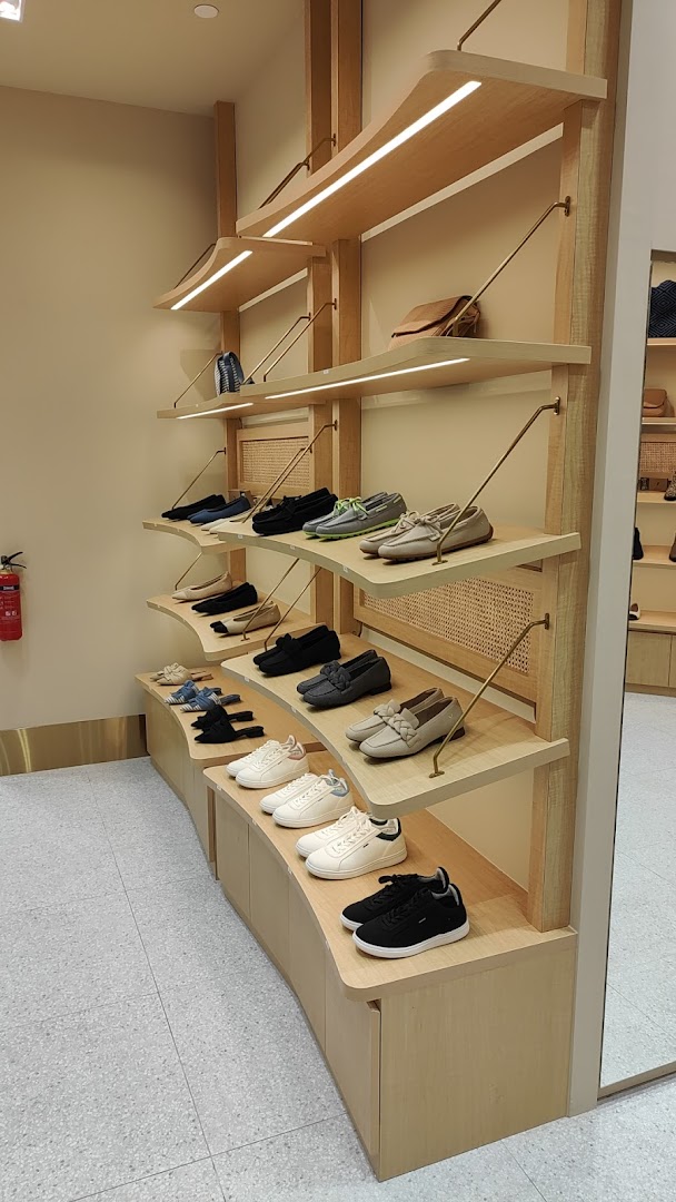 Interior view of a shoe store with multiple pairs of shoes displayed on wooden shelves.