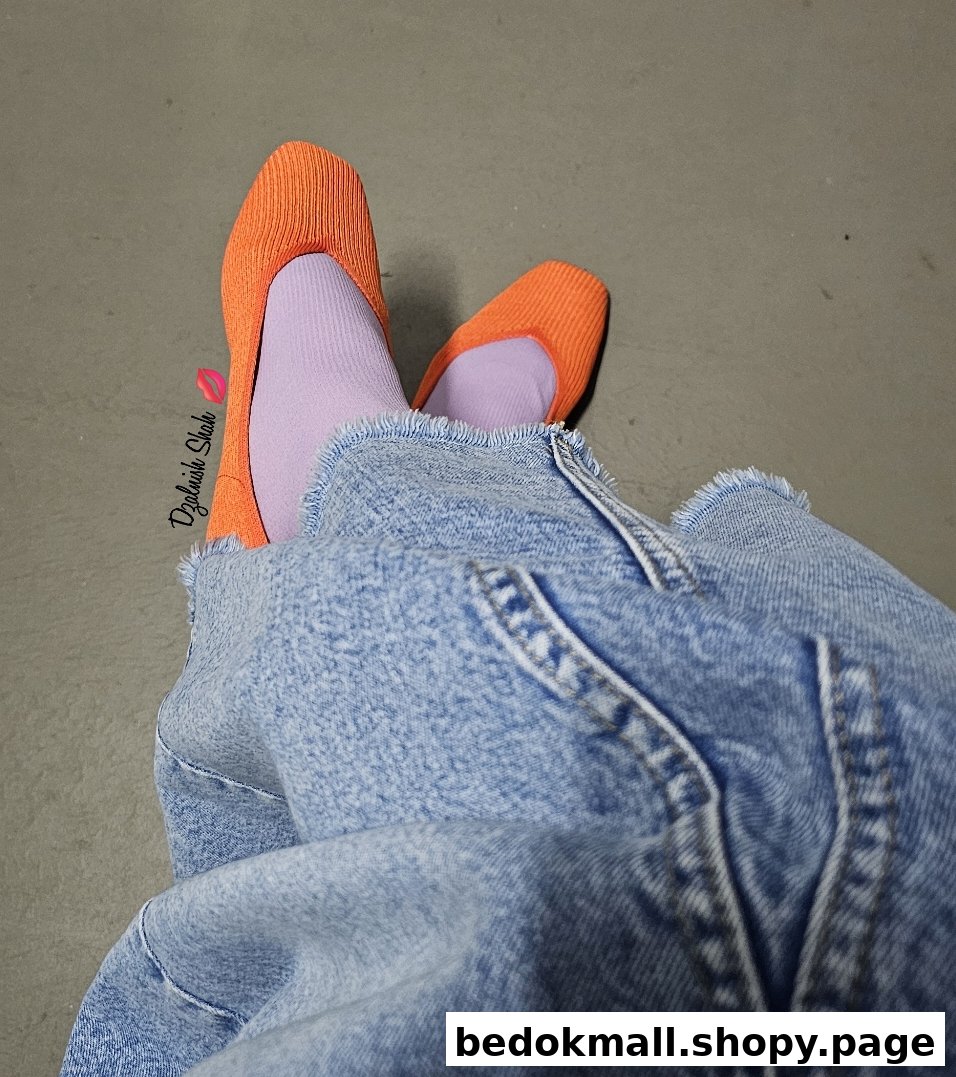Person wearing orange shoes and purple socks with blue denim pants.
