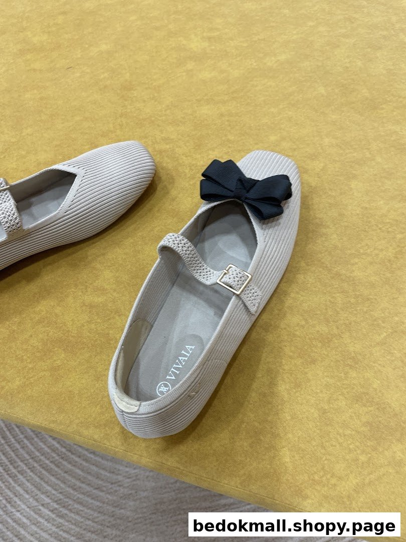 A pair of beige shoes with a black bow on a yellow surface.