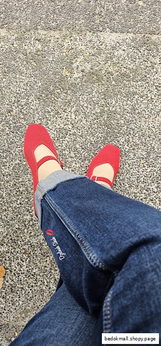 Person wearing red shoes and blue jeans, resting on a textured ground.