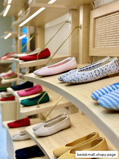Colorful shoes displayed on wooden shelves inside a retail store.
