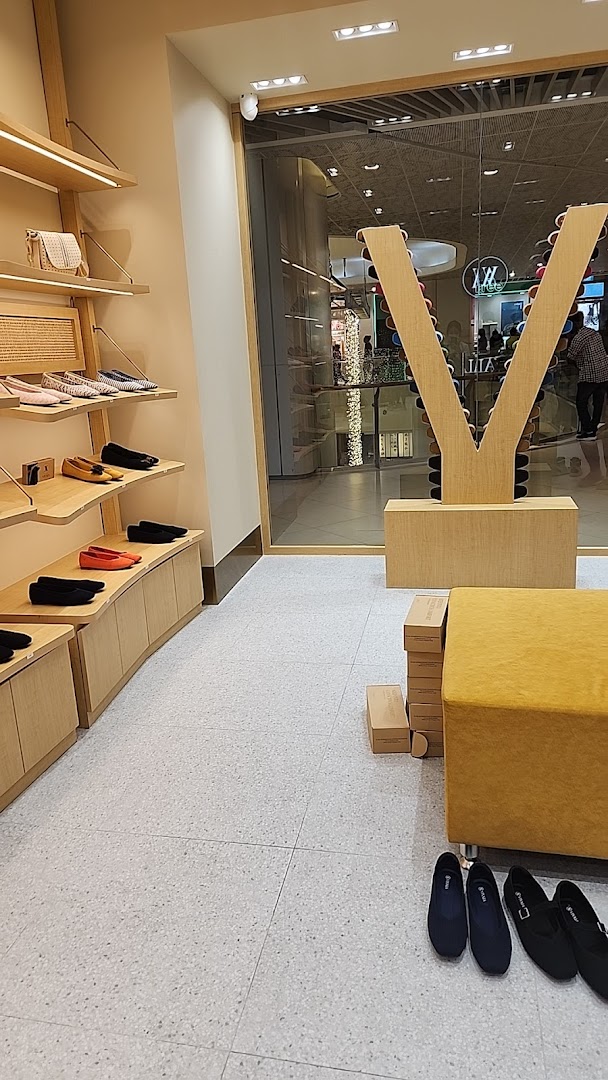 Interior view of a shoe shop with shelves displaying shoes and bags.