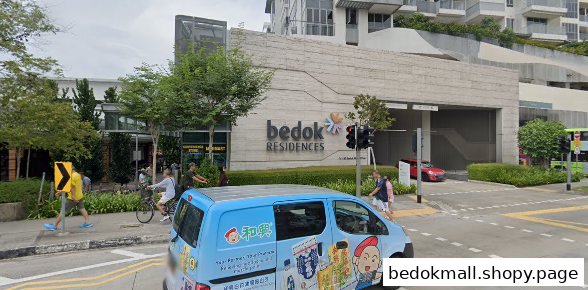 Exterior view of a large building complex and street with people and a blue van.