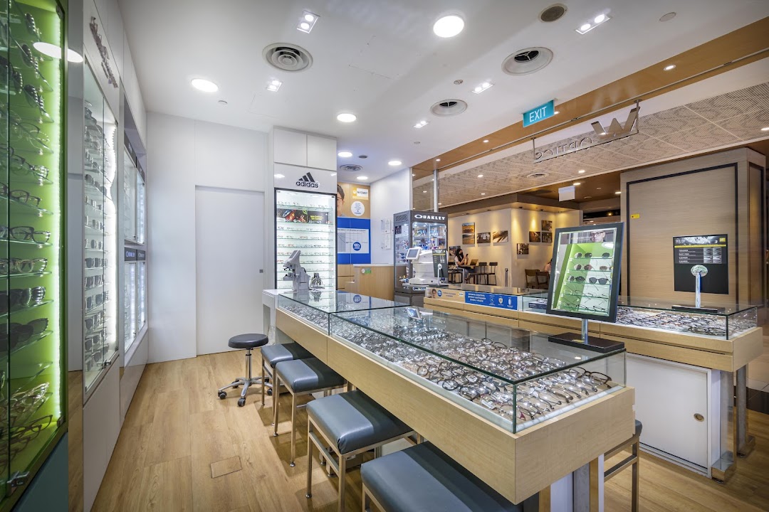 Interior of an optics shop with eyeglasses displays and an eye examination area.