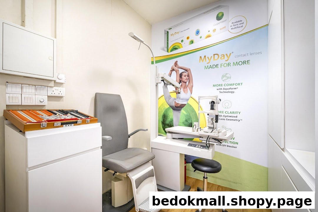 An eye examination room with equipment and contact lens advertising.