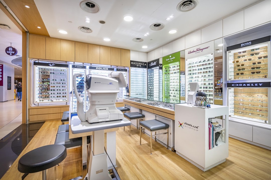 Interior of an optical shop with display cases and eye examination equipment.