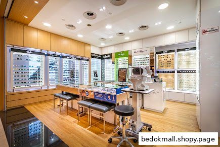 Interior of an optical shop with display cases, eye exam equipment, and seating.