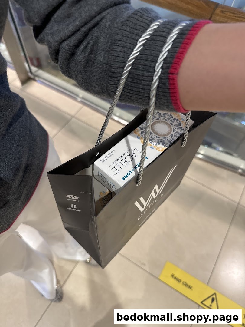 Person holding a W Optics shopping bag with contact lenses inside.