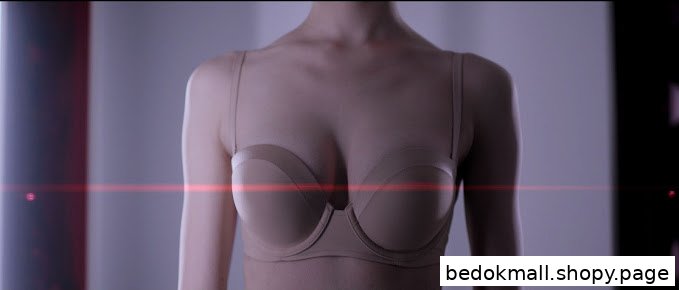 Torso wearing a beige bra with a red light beam across the chest.