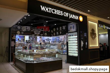 Shop front of 'Watches of Japan' displaying numerous watches inside a mall.