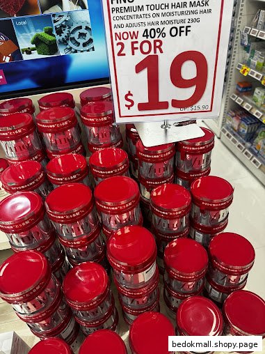 Display of red-lidded hair masks with a promotional price sign in a shop.