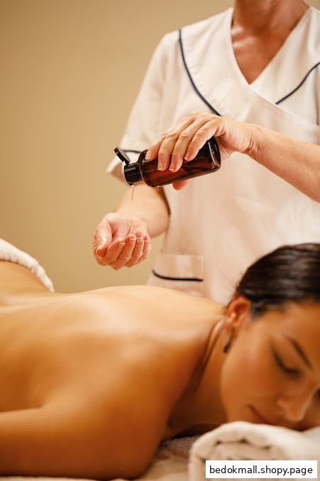 Therapist pouring massage oil onto client's hand during a wellness treatment.