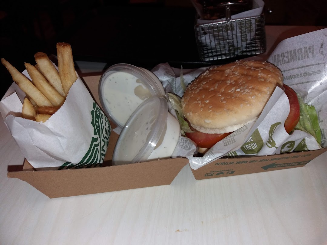 A burger, fries, and dipping sauces in a Wingstop take-out container.