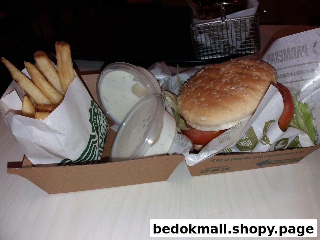 A burger, fries, and dipping sauces in a Wingstop take-out container.