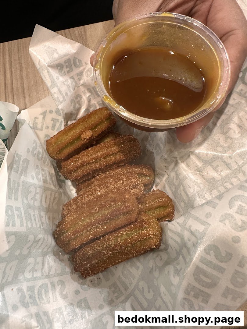 Churros with dipping sauce in a basket with branded paper.