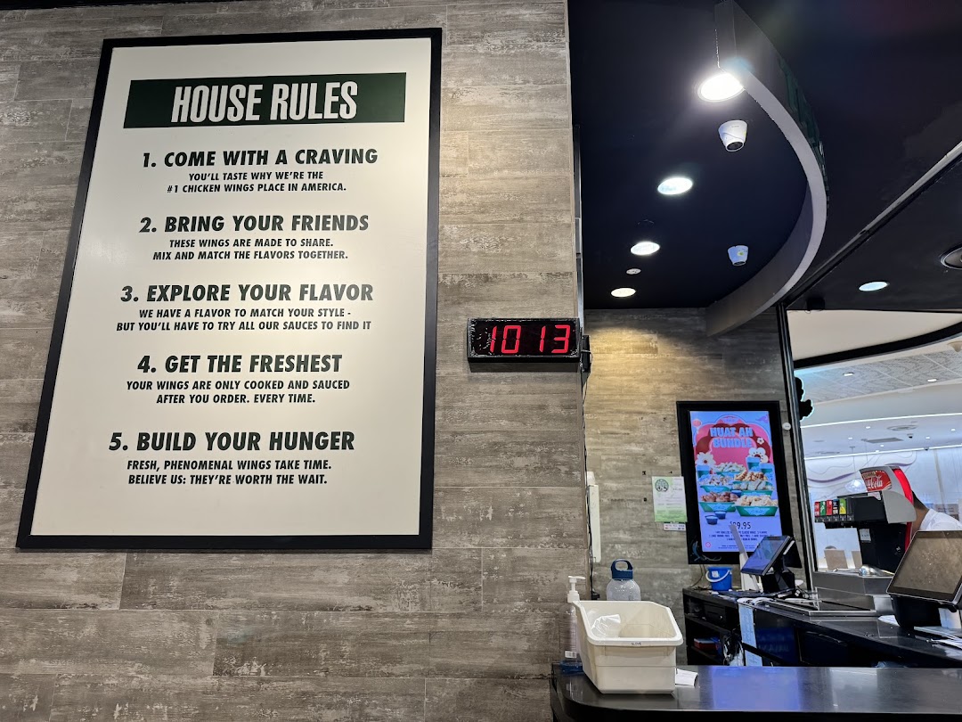 Interior shot of Wingstop with a 'House Rules' sign and order counter.
