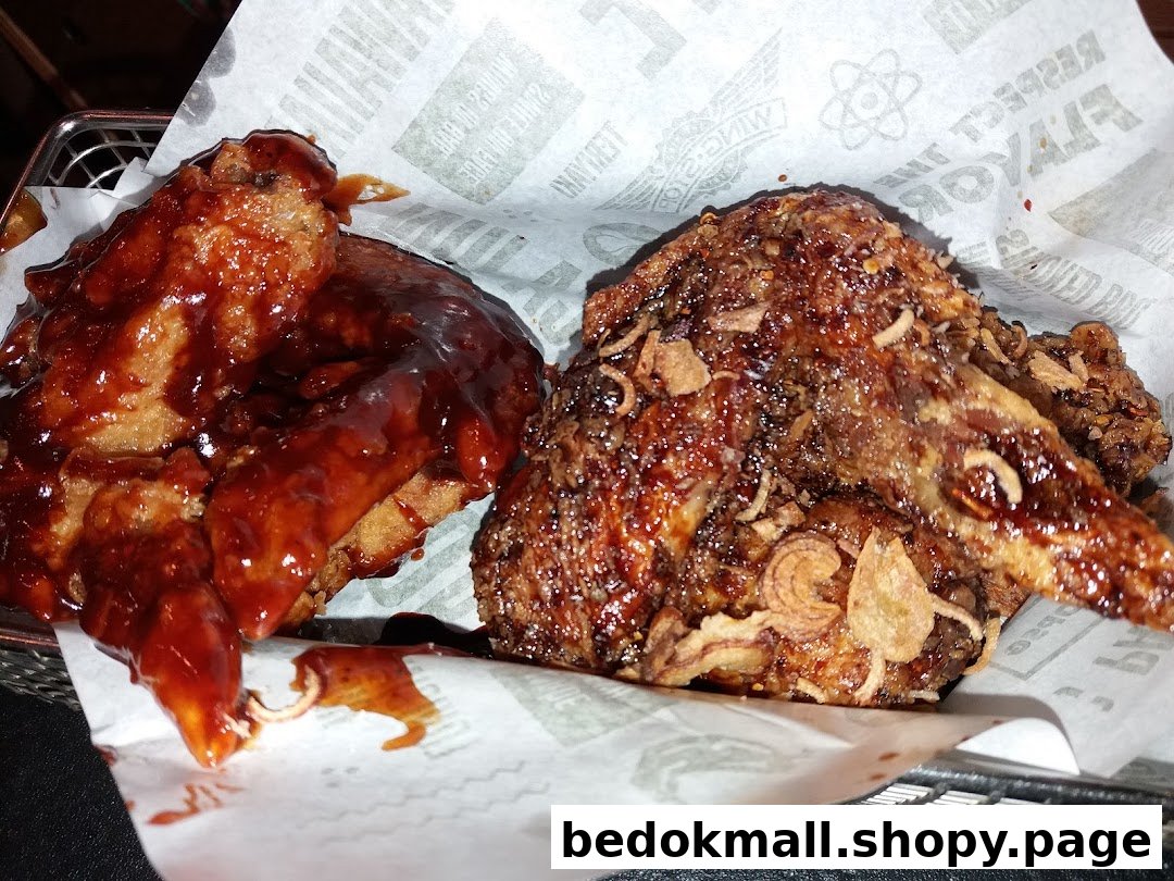 Two sauced chicken wings in a basket lined with branded paper.