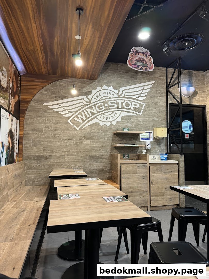 Interior view of Wingstop with dining tables, chairs, and brand logo on the wall.