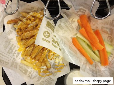 Fries with cheese sauce, carrot and celery sticks, and dip in baskets.