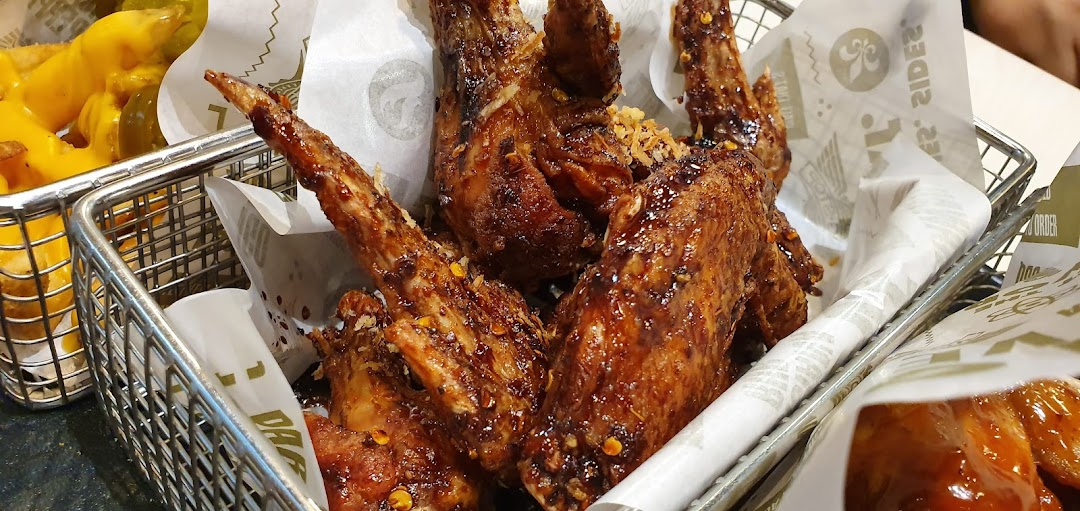 Close-up of chicken wings and fries in metal baskets.