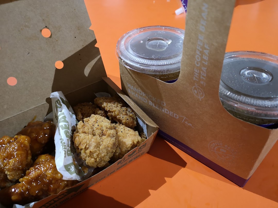 A box of chicken wings and nuggets with two drinks in a carrier.