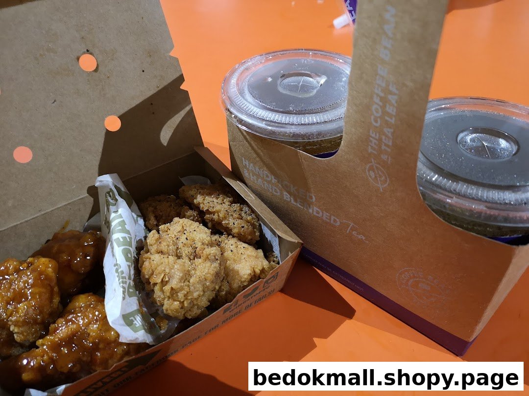 A box of chicken wings and nuggets with two drinks in a carrier.
