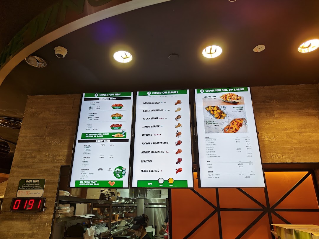 Digital menu boards showing food items and prices inside a restaurant.