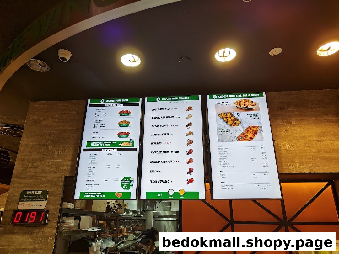 Digital menu boards showing food items and prices inside a restaurant.