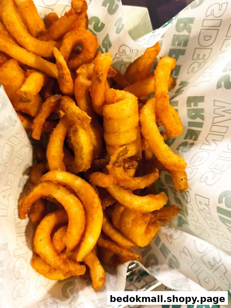 A close-up of golden curly fries in a basket with Wingstop branded paper.