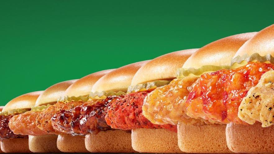 A row of various chicken sandwiches/sliders with different toppings on a green background.