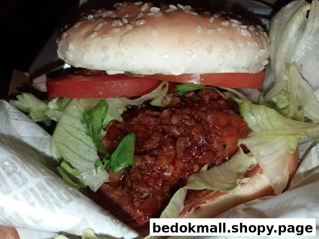 Close-up of a burger with a saucy patty, lettuce, and tomato.