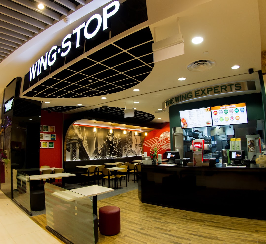 Interior view of Wingstop restaurant with counter, menu screens, and seating area.