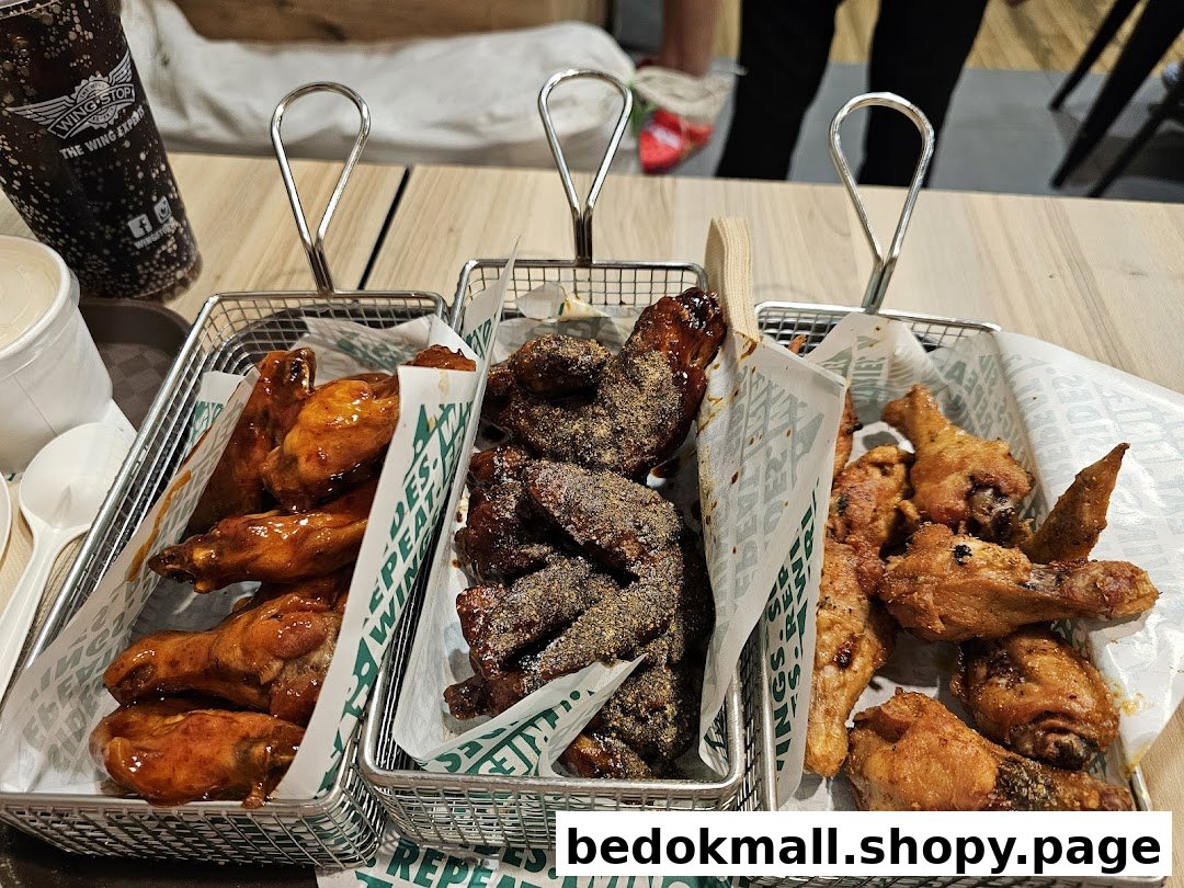 Three baskets of chicken wings and a drink on a table.