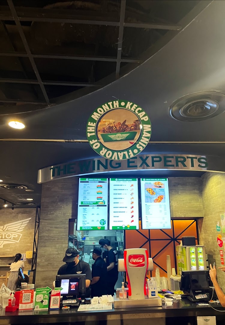 Interior shot of Wingstop with counter, staff, and digital menu boards.