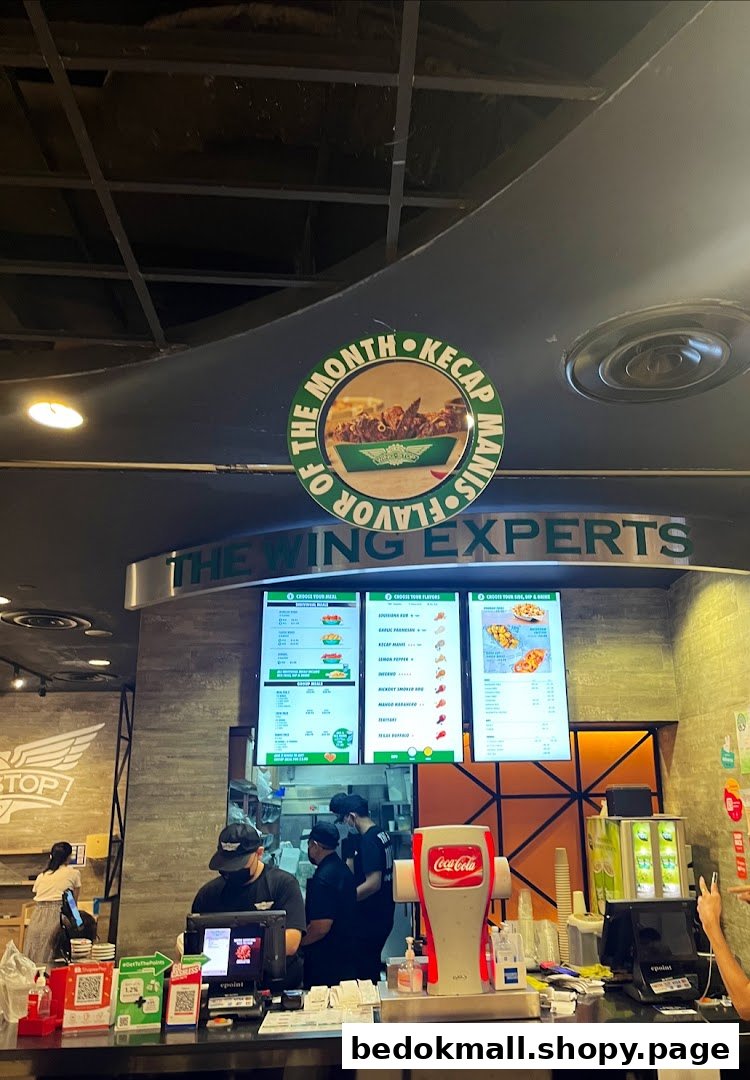 Interior shot of Wingstop with counter, staff, and digital menu boards.