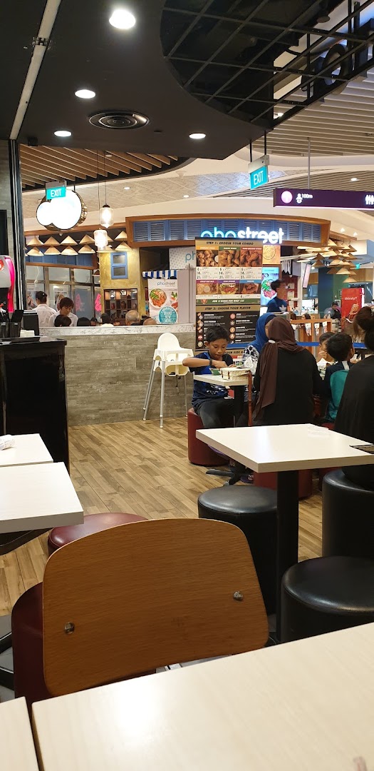 Interior view of a food court with customers dining and a menu board visible.