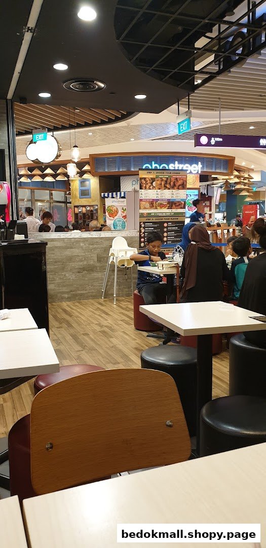 Interior view of a food court with customers dining and a menu board visible.