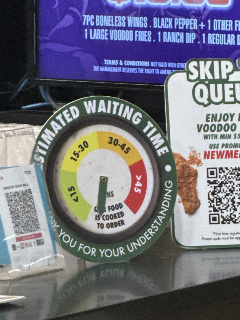Estimated waiting time sign, partial menu screen, and QR codes inside a shop.