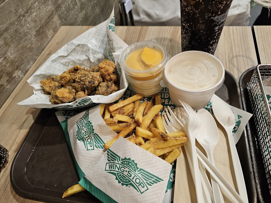 A tray with fried chicken, fries, sauces, a drink, and utensils.