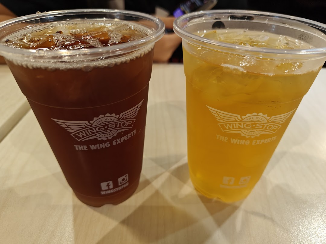 Two Wingstop branded drinks in plastic cups on a table.