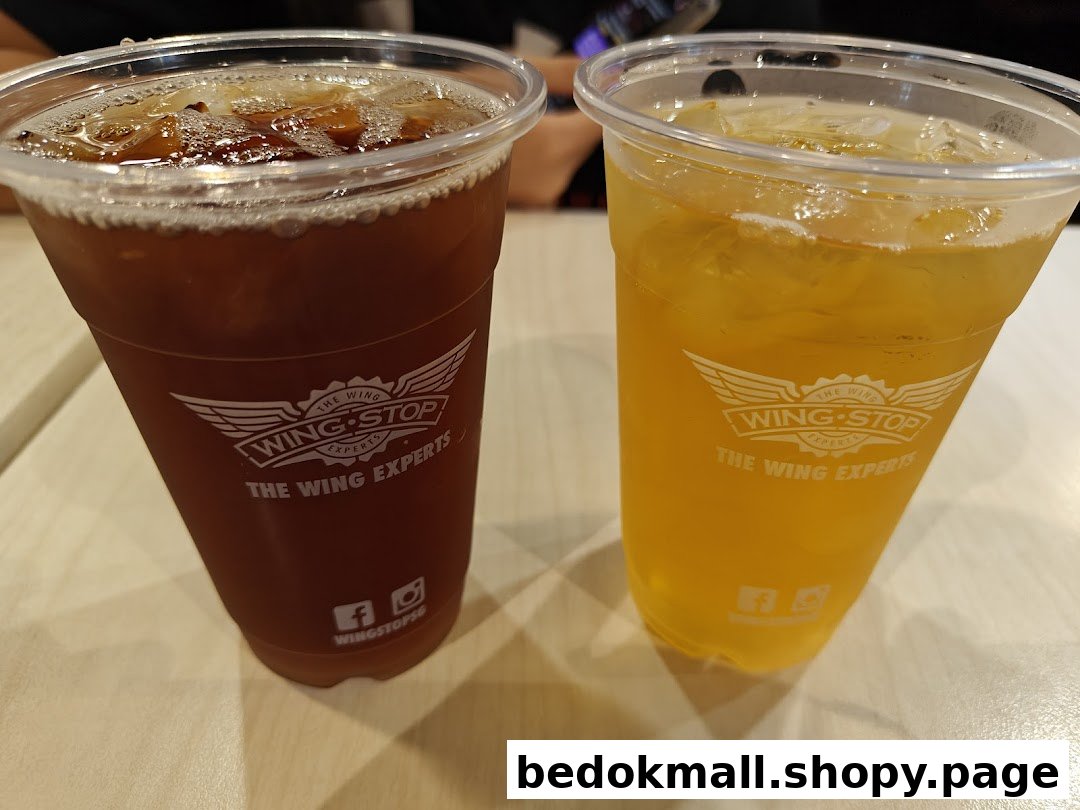 Two Wingstop branded drinks in plastic cups on a table.