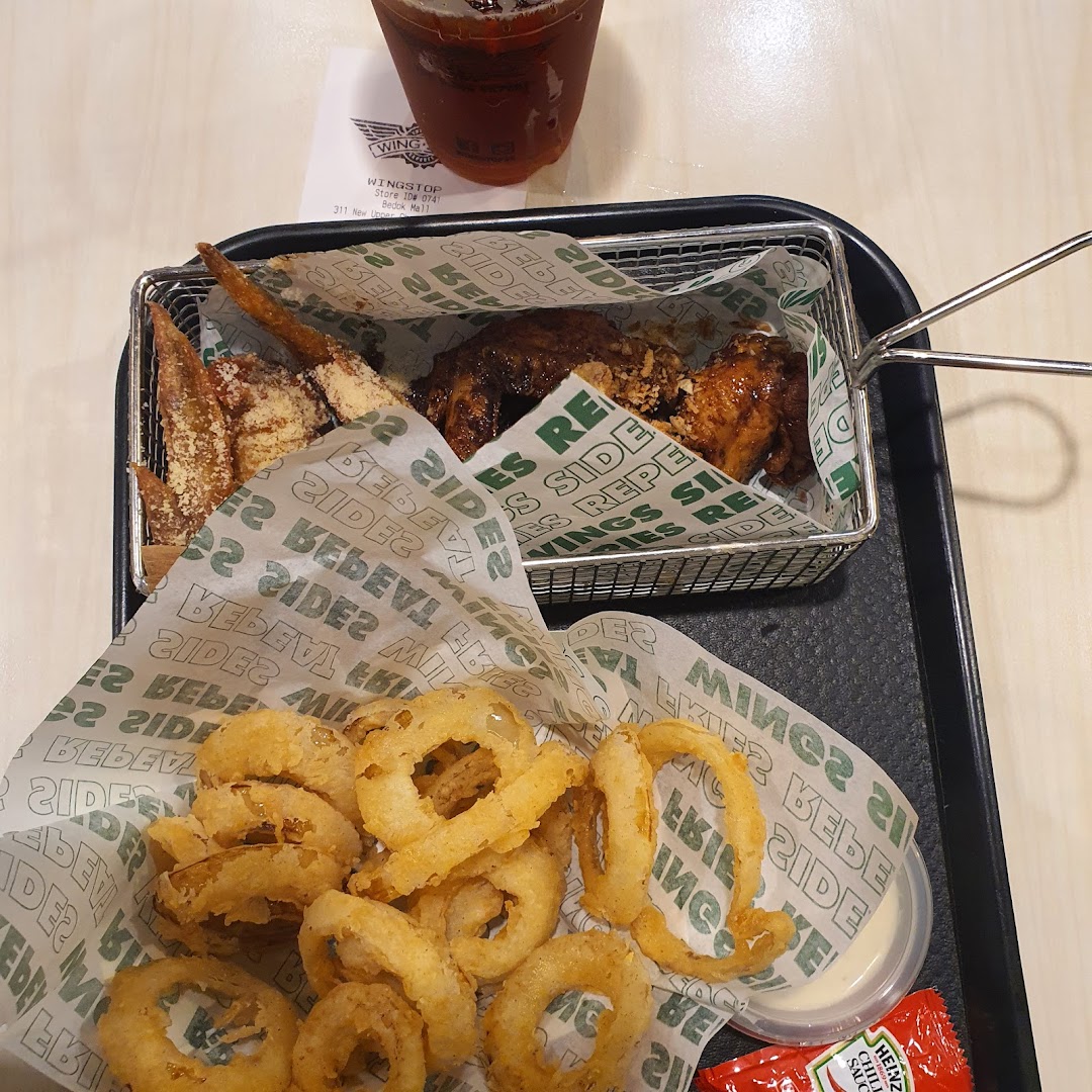 A tray with chicken wings, onion rings, and a drink.