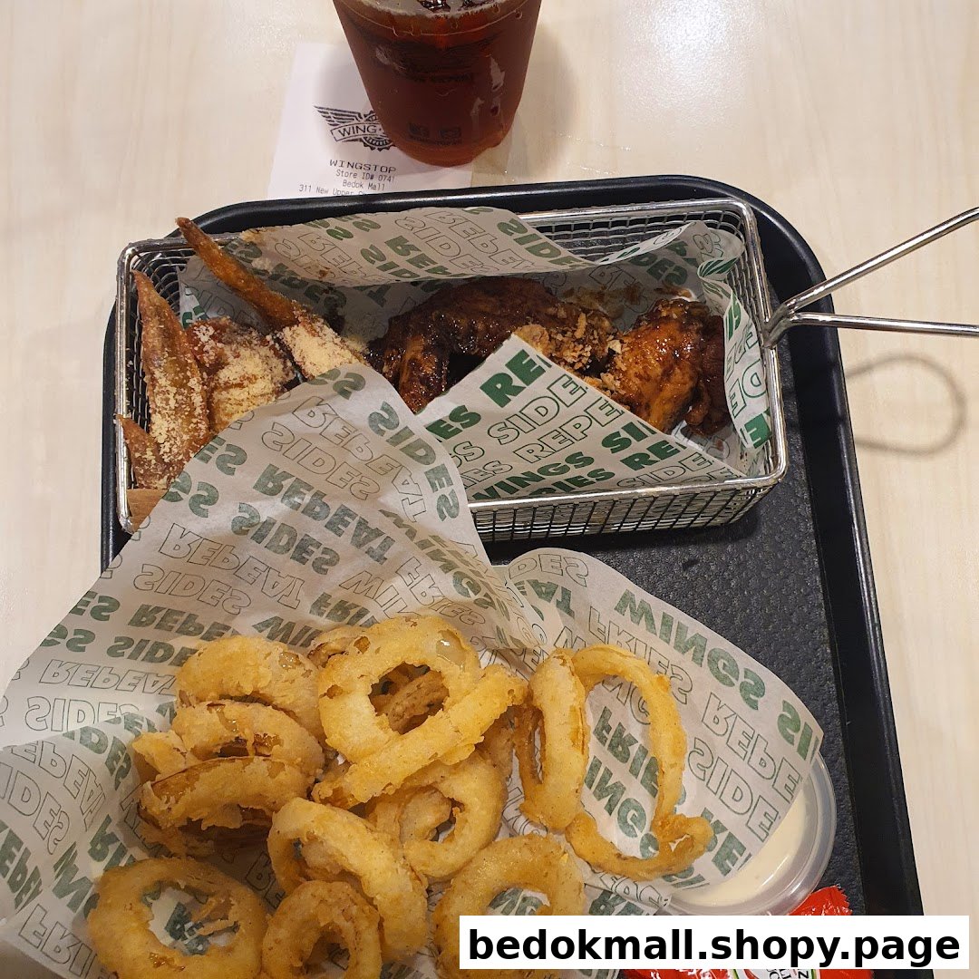 A tray with chicken wings, onion rings, and a drink.