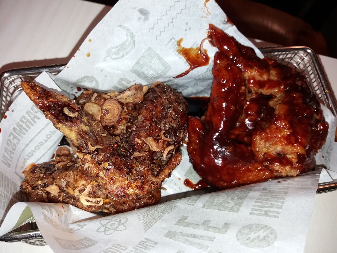 Two chicken wings, one dark and one red, served in a basket.
