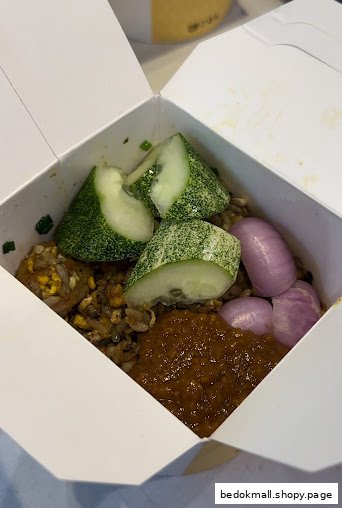 Fried rice with cucumber, red onions, and chili paste in a takeout box.