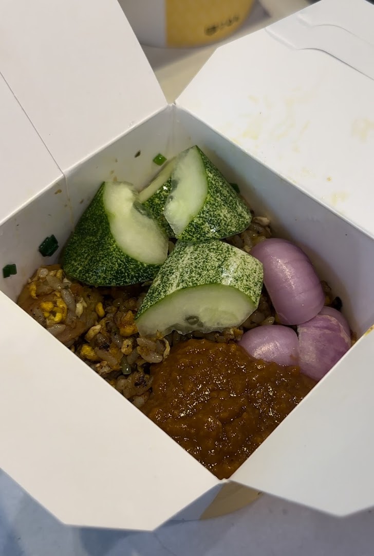 Takeout box with fried rice, cucumber, onions, and sauce.