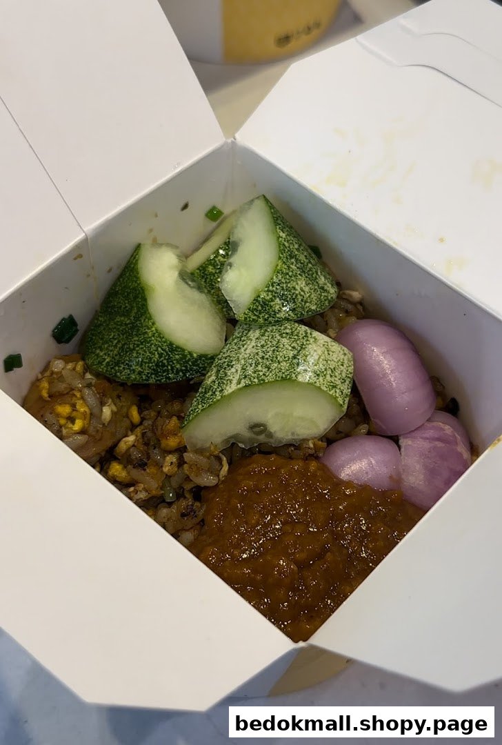 Takeout box with fried rice, cucumber, onions, and sauce.