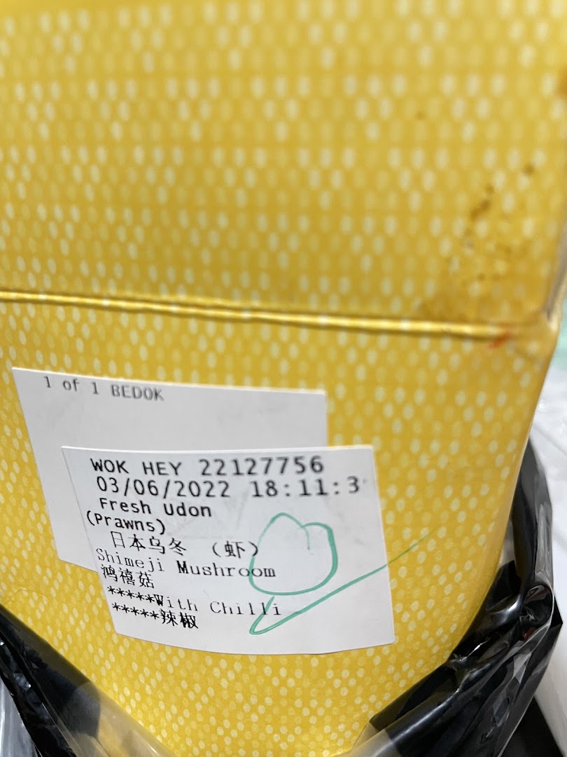Yellow food container with an order label for udon and mushrooms.